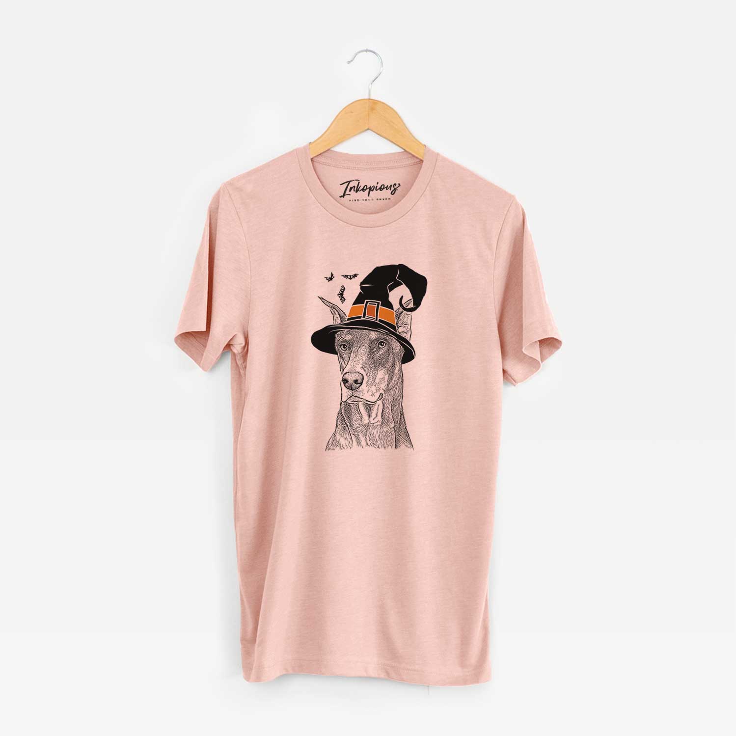 Hand-drawn sketch of RJ the Doberman Pinscher wearing a witch hat on a Peach Unisex crewneck