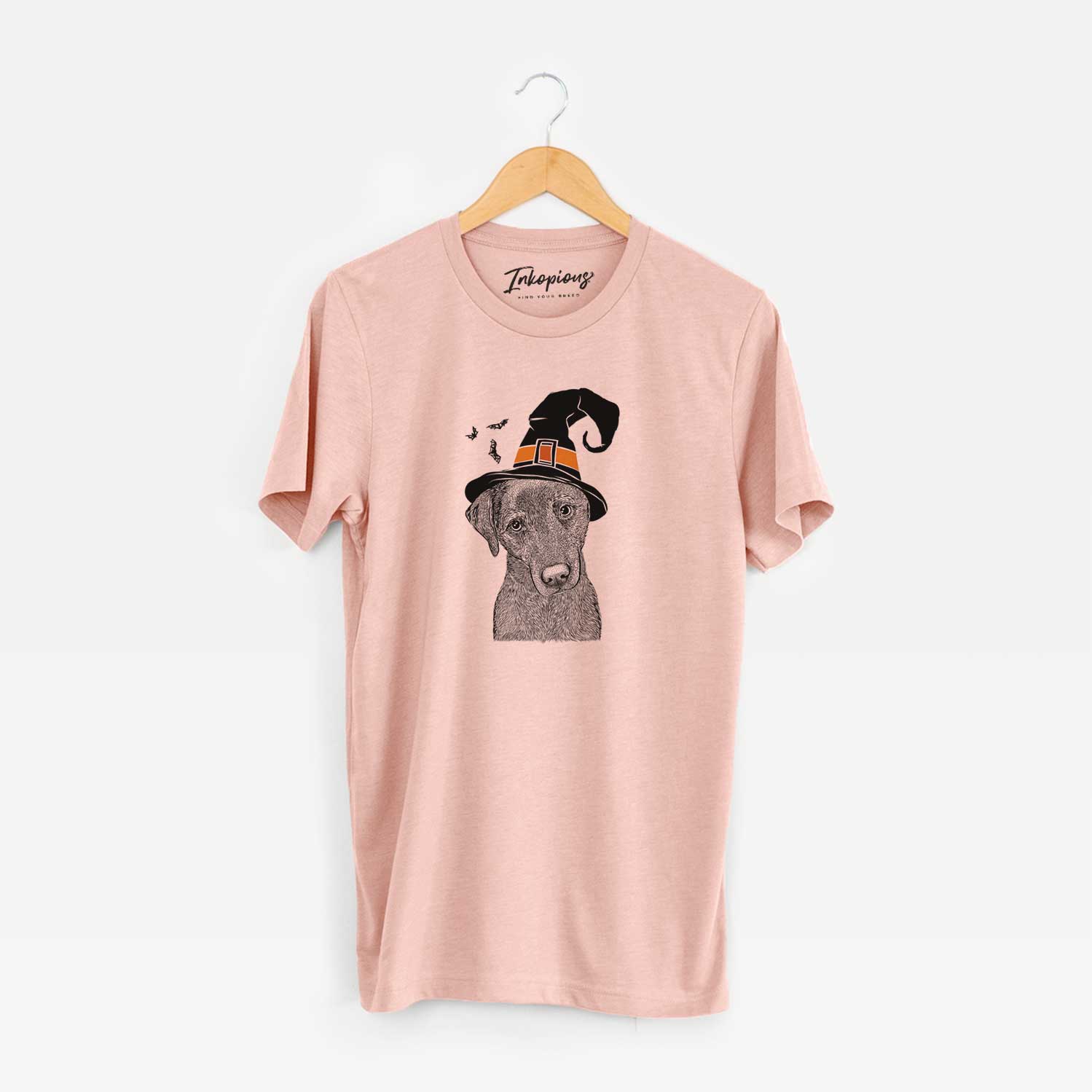 Hand-drawn sketch of Sadie the Whipador wearing a witch hat on a Peach Unisex crewneck