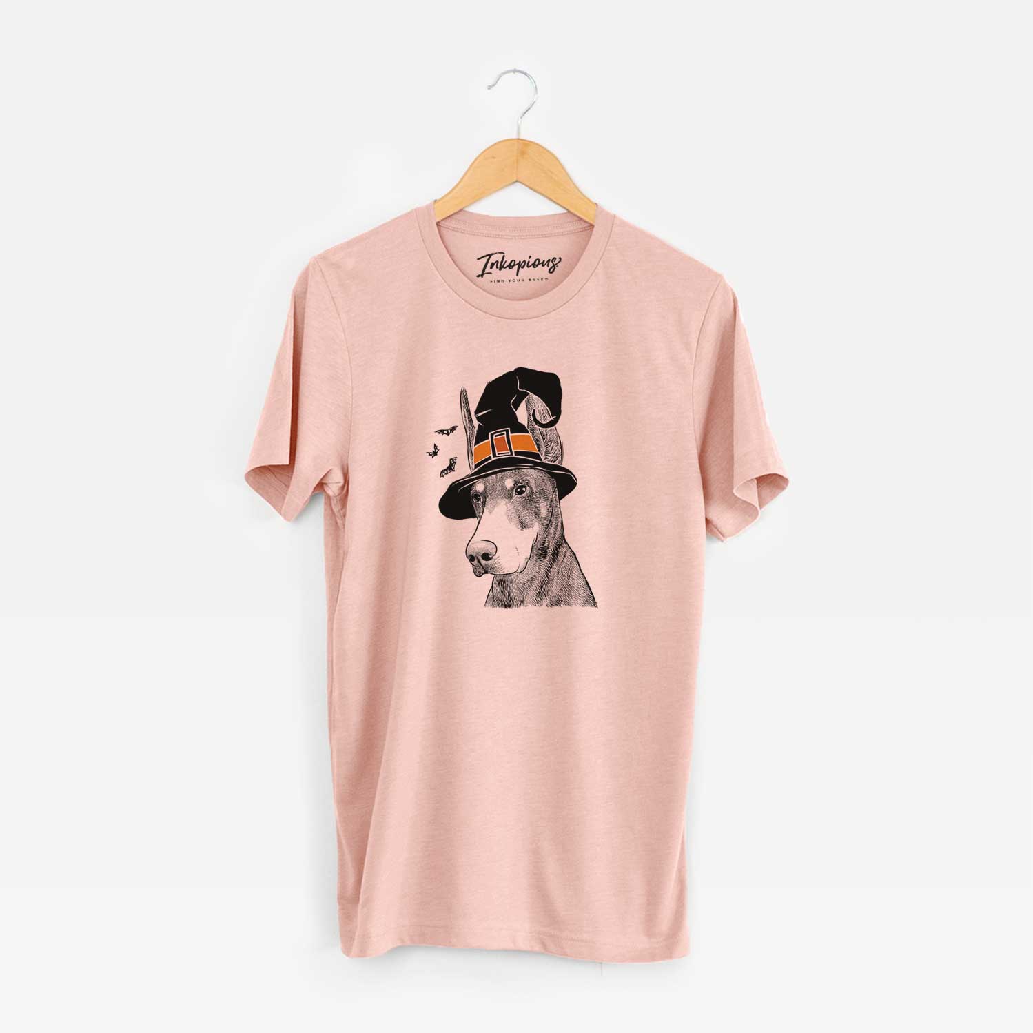 Hand-drawn sketch of Sunny the Doberman Pinscher wearing a witch hat on a Peach Unisex crewneck