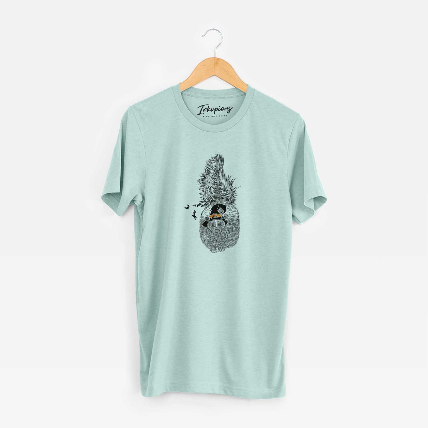 Hand-drawn sketch of Tibbs the Skunk wearing a witch hat on a Heather Sage Unisex crewneck