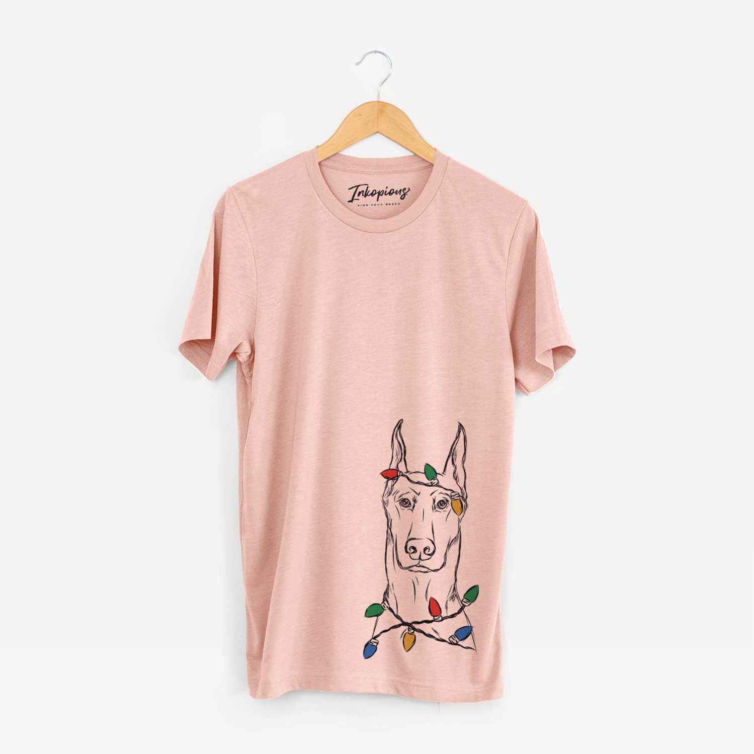 Hand-drawn sketch of Ace the Doberman Pinscher wrapped in Christmas lights on a Peach Unisex crewneck