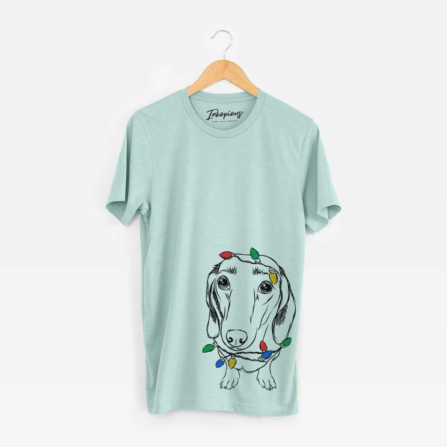 Hand-drawn sketch of Annabelle the Dachshund wrapped in Christmas lights on a Heather Sage Unisex crewneck