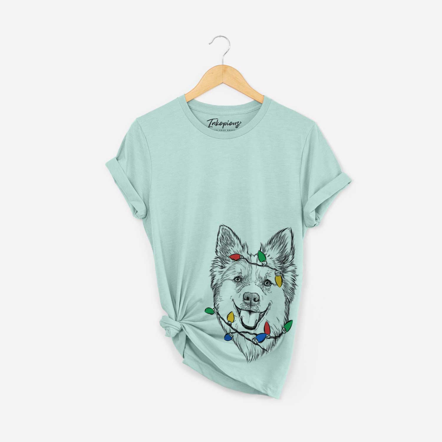 Hand-drawn sketch of Ari the Icelandic Sheepdog wrapped in Christmas lights on a Heather Sage Unisex crewneck