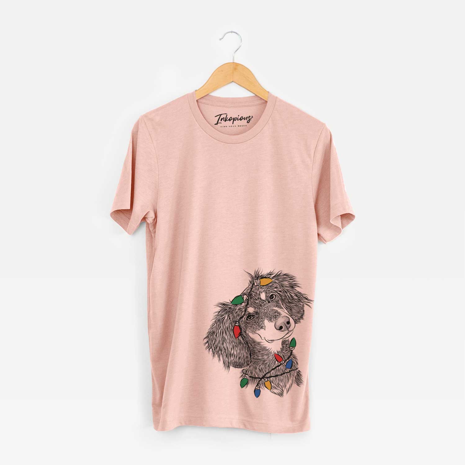Hand-drawn sketch of Bailey the Long Haired Dachshund wrapped in Christmas lights on a Peach Unisex crewneck