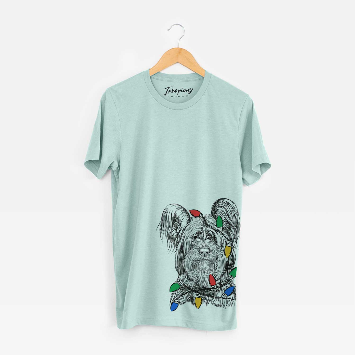 Hand-drawn sketch of Bandit the Skye Terrier wrapped in Christmas lights on a Heather Sage Unisex crewneck