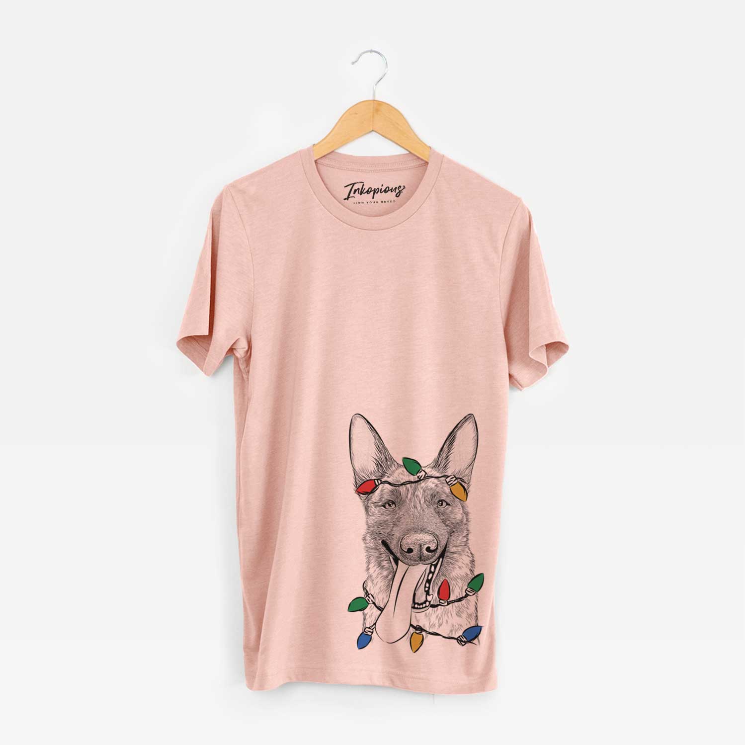 Hand-drawn sketch of Bessa the Dutch Shepherd wrapped in Christmas lights on a Peach Unisex crewneck