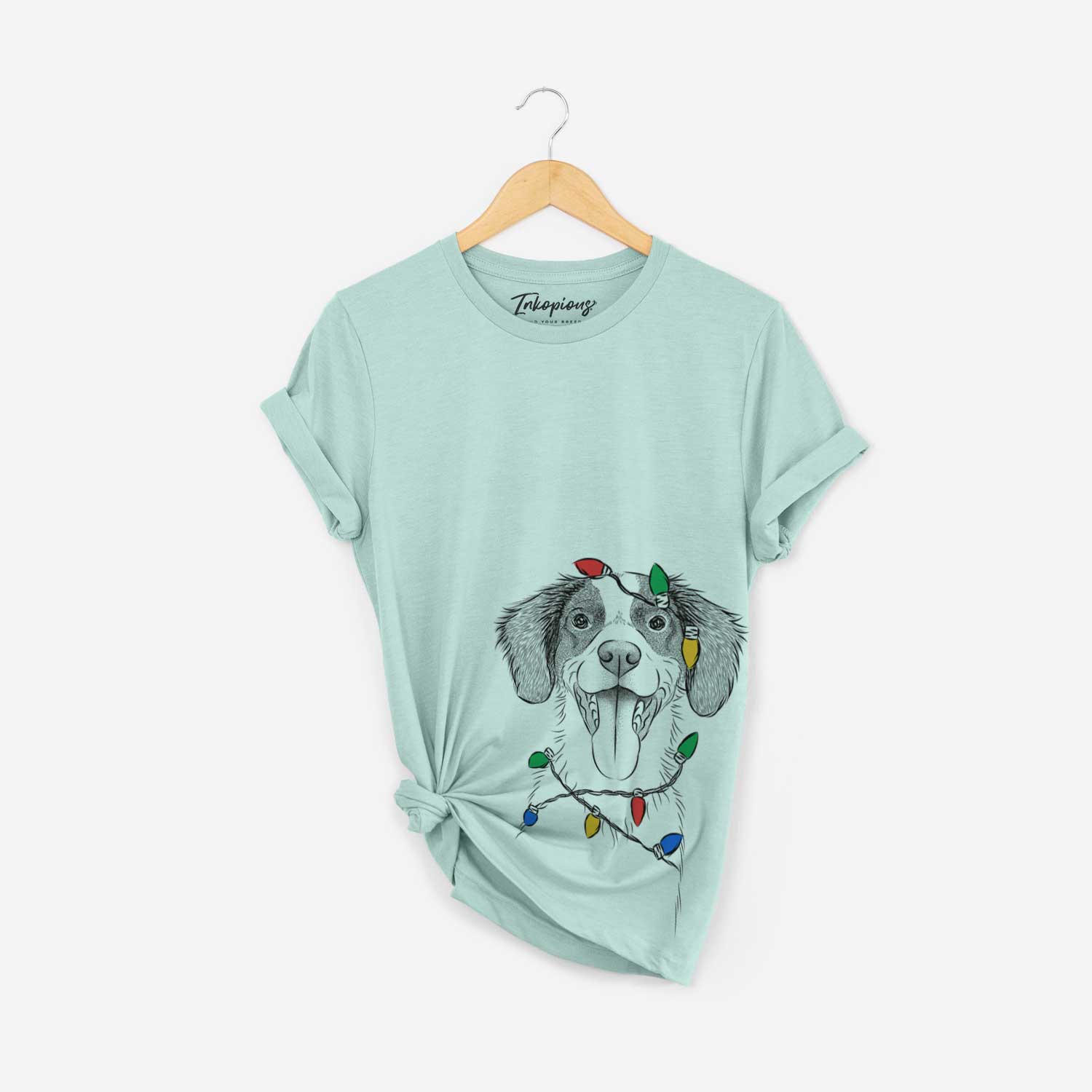 Hand-drawn sketch of Birdie the Brittany wrapped in Christmas lights on a Heather Sage Unisex crewneck