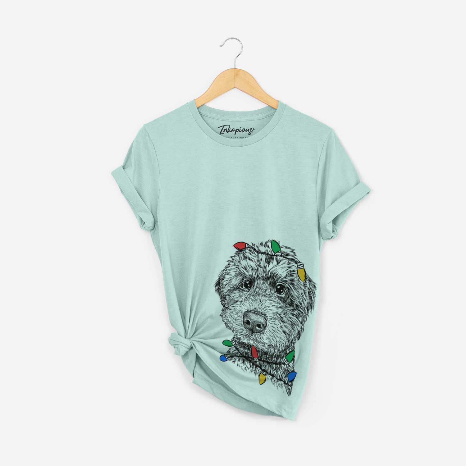 Hand-drawn sketch of Bowser the Whoodle wrapped in Christmas lights on a Heather Sage Unisex crewneck