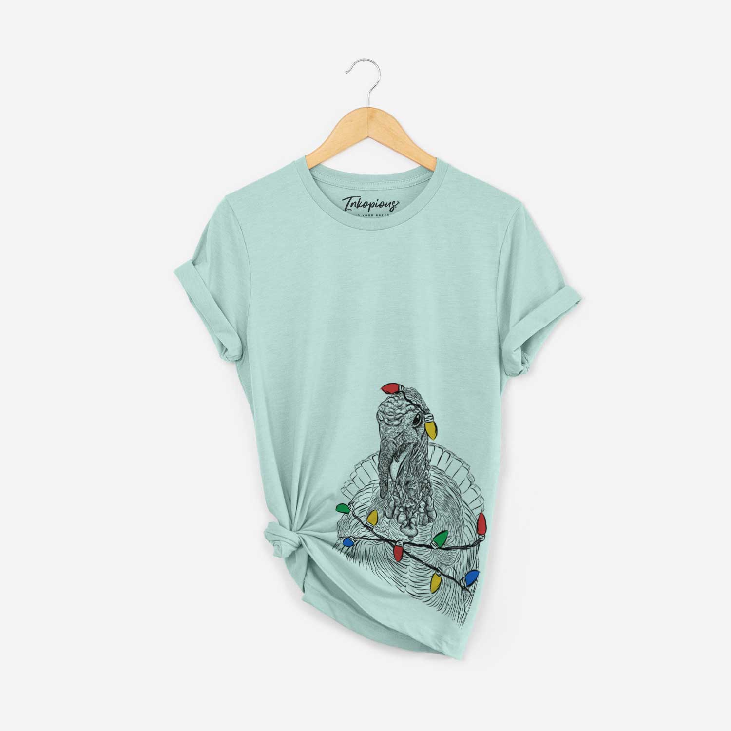 Hand-drawn sketch of Brady the Turkey wrapped in Christmas lights on a Heather Sage Unisex crewneck