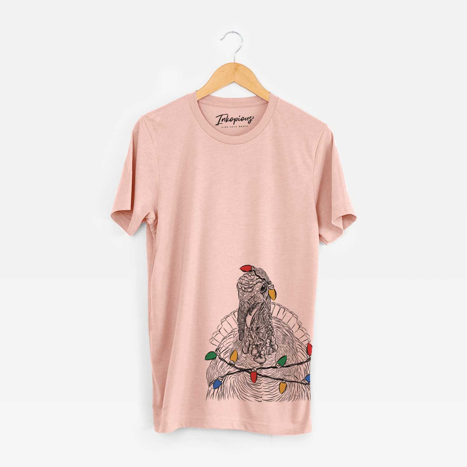 Hand-drawn sketch of Brady the Turkey wrapped in Christmas lights on a Peach Unisex crewneck