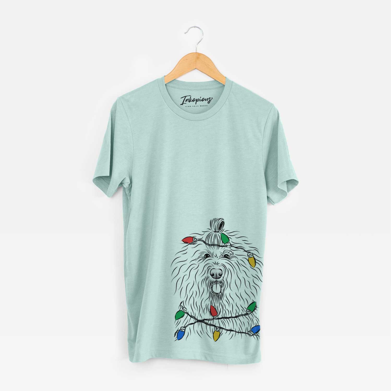Hand-drawn sketch of Brody the Old English Sheepdog wrapped in Christmas lights on a Heather Sage Unisex crewneck