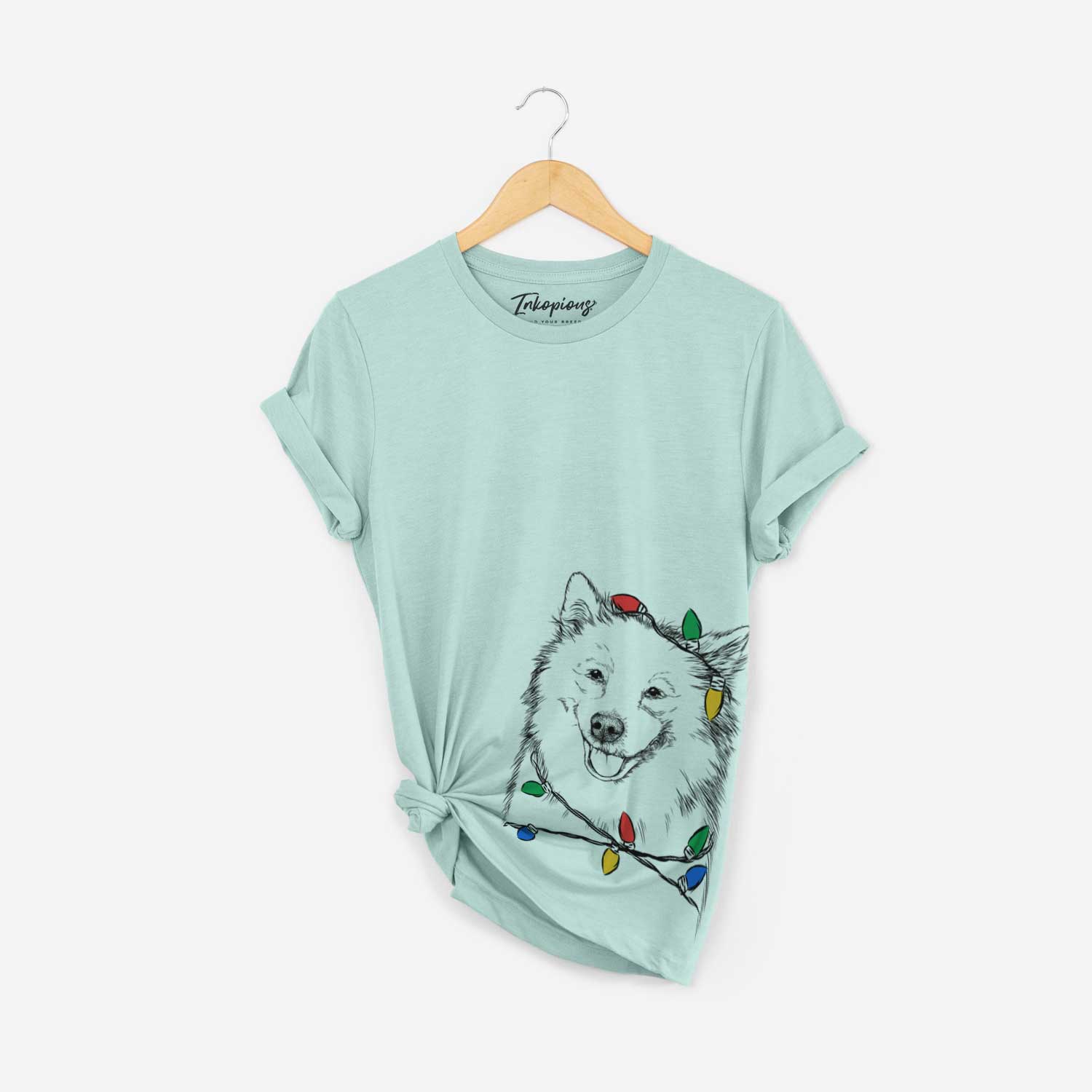 Hand-drawn sketch of Caico the Samoyed wrapped in Christmas lights on a Heather Sage Unisex crewneck