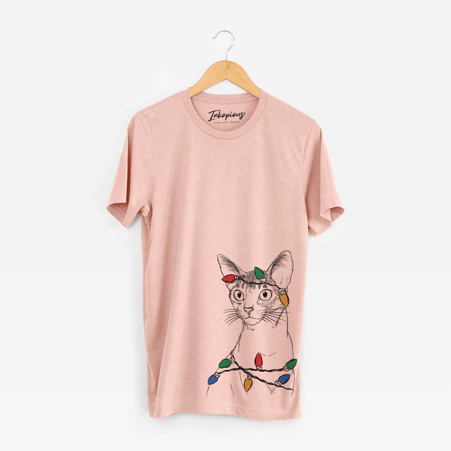 Hand-drawn sketch of Cedric the Abyssinian Cat wrapped in Christmas lights on a Peach Unisex crewneck