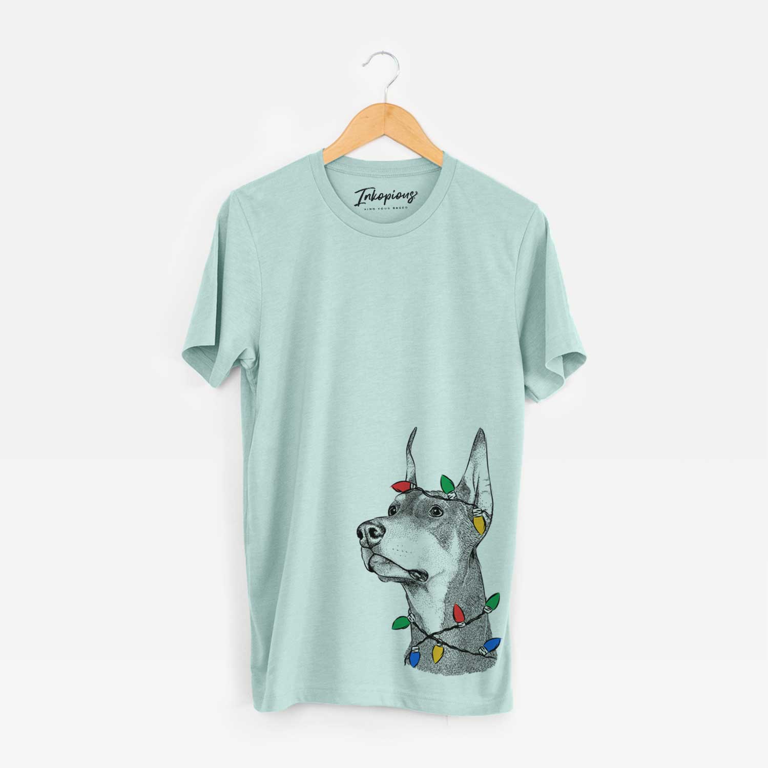 Hand-drawn sketch of Cenza the Doberman Pinscher wrapped in Christmas lights on a Heather Sage Unisex crewneck