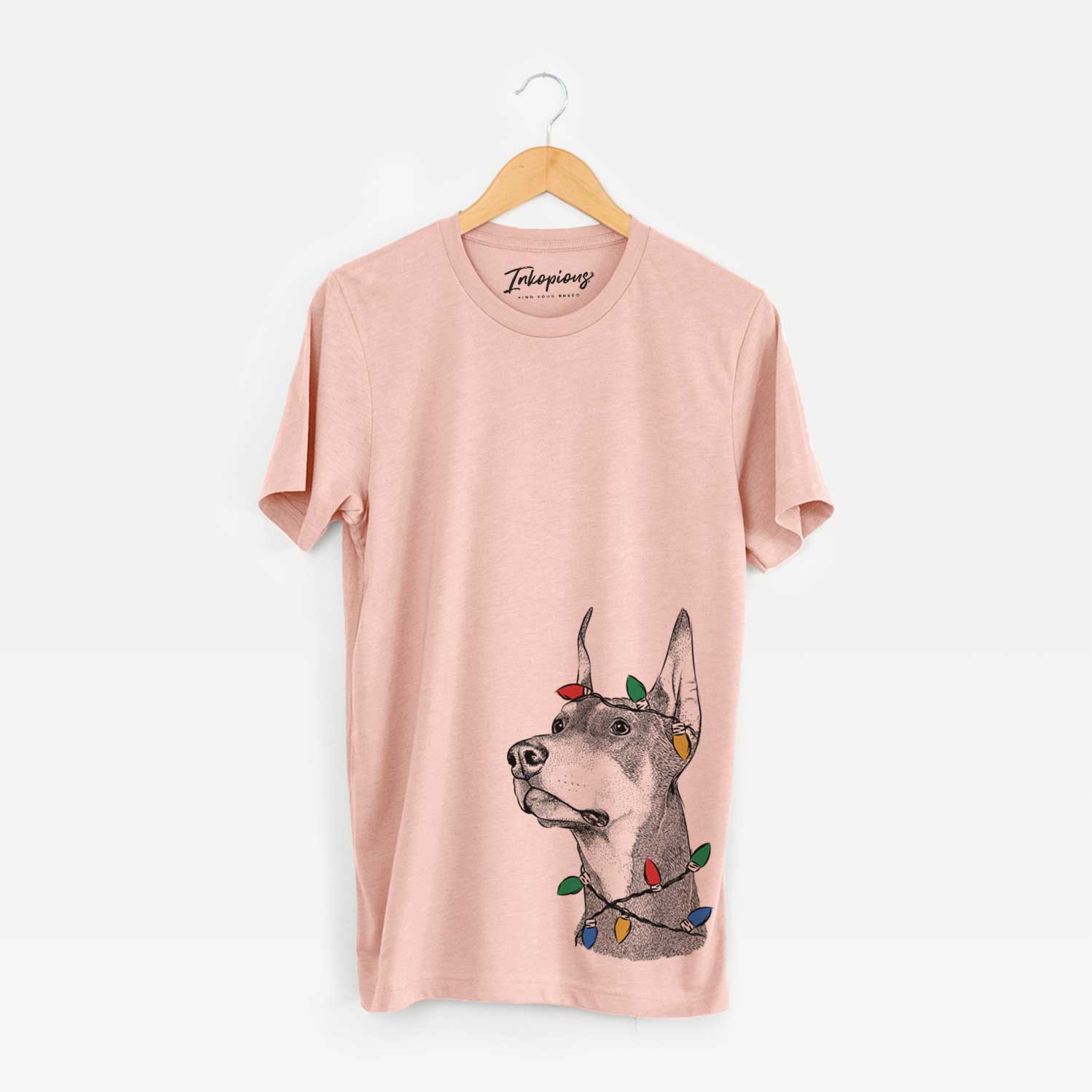 Hand-drawn sketch of Cenza the Doberman Pinscher wrapped in Christmas lights on a Peach Unisex crewneck