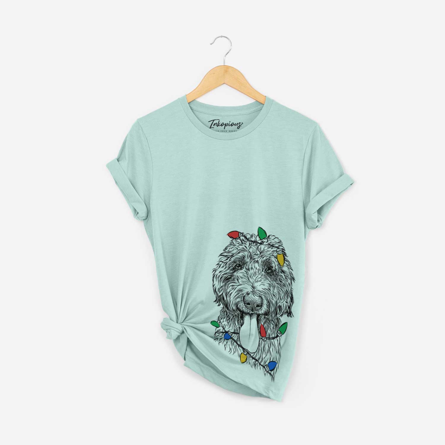Hand-drawn sketch of CiCi Paulk the Aussiedoodle wrapped in Christmas lights on a Heather Sage Unisex crewneck