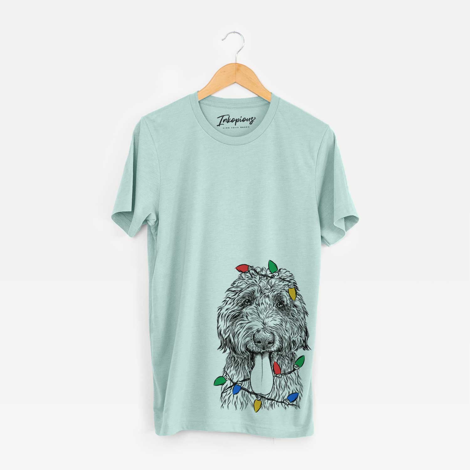Hand-drawn sketch of CiCi Paulk the Aussiedoodle wrapped in Christmas lights on a Heather Sage Unisex crewneck