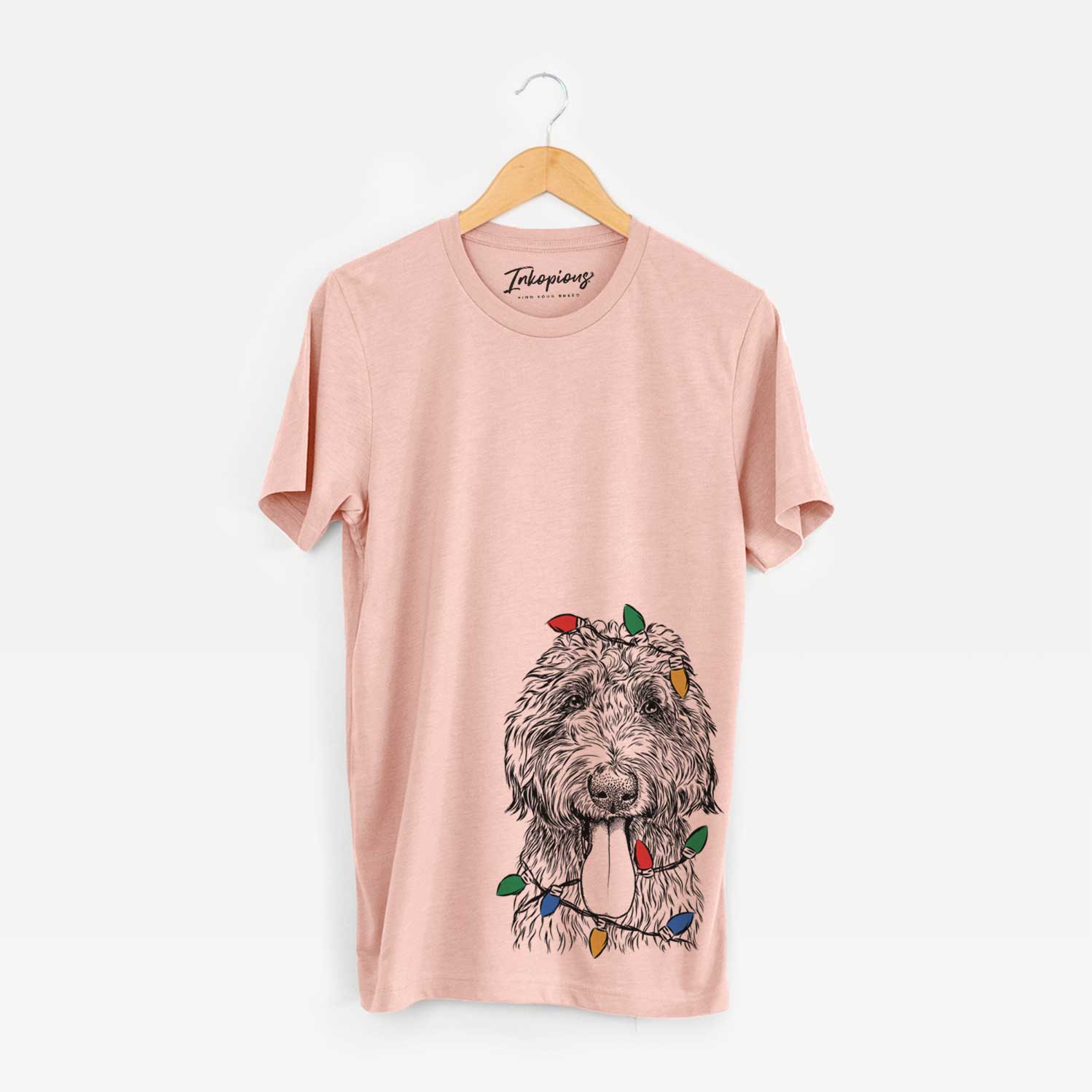 Hand-drawn sketch of CiCi Paulk the Aussiedoodle wrapped in Christmas lights on a Peach Unisex crewneck