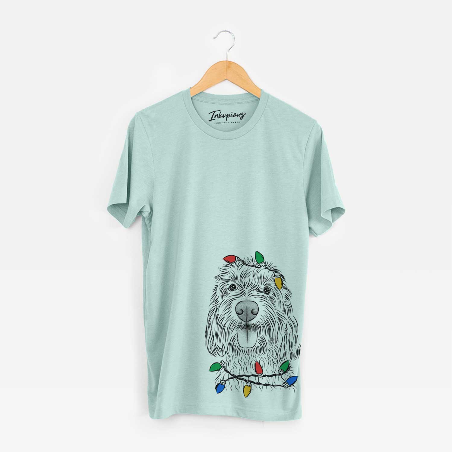 Hand-drawn sketch of Clover the Cockapoo wrapped in Christmas lights on a Heather Sage Unisex crewneck