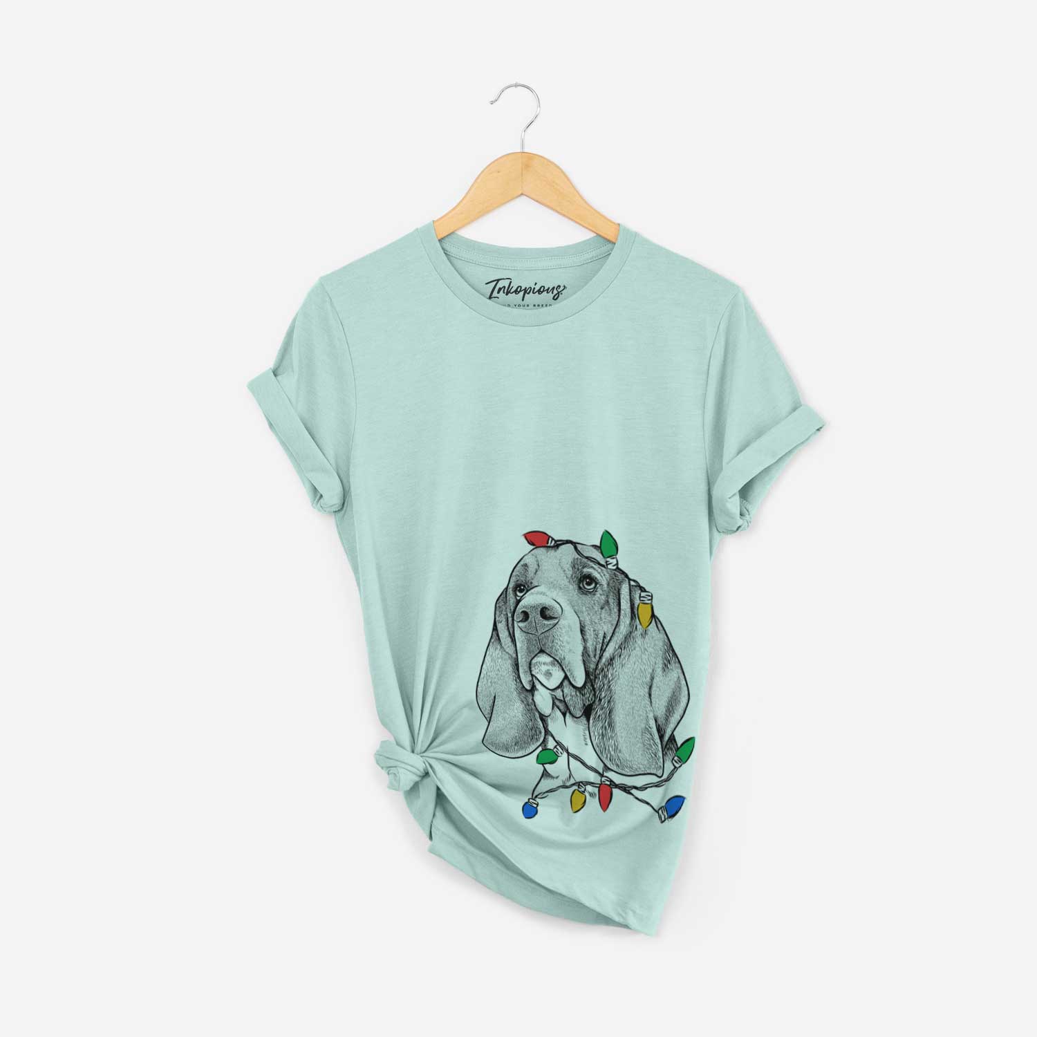 Hand-drawn sketch of Cooper the Basset Hound wrapped in Christmas lights on a Heather Sage Unisex crewneck