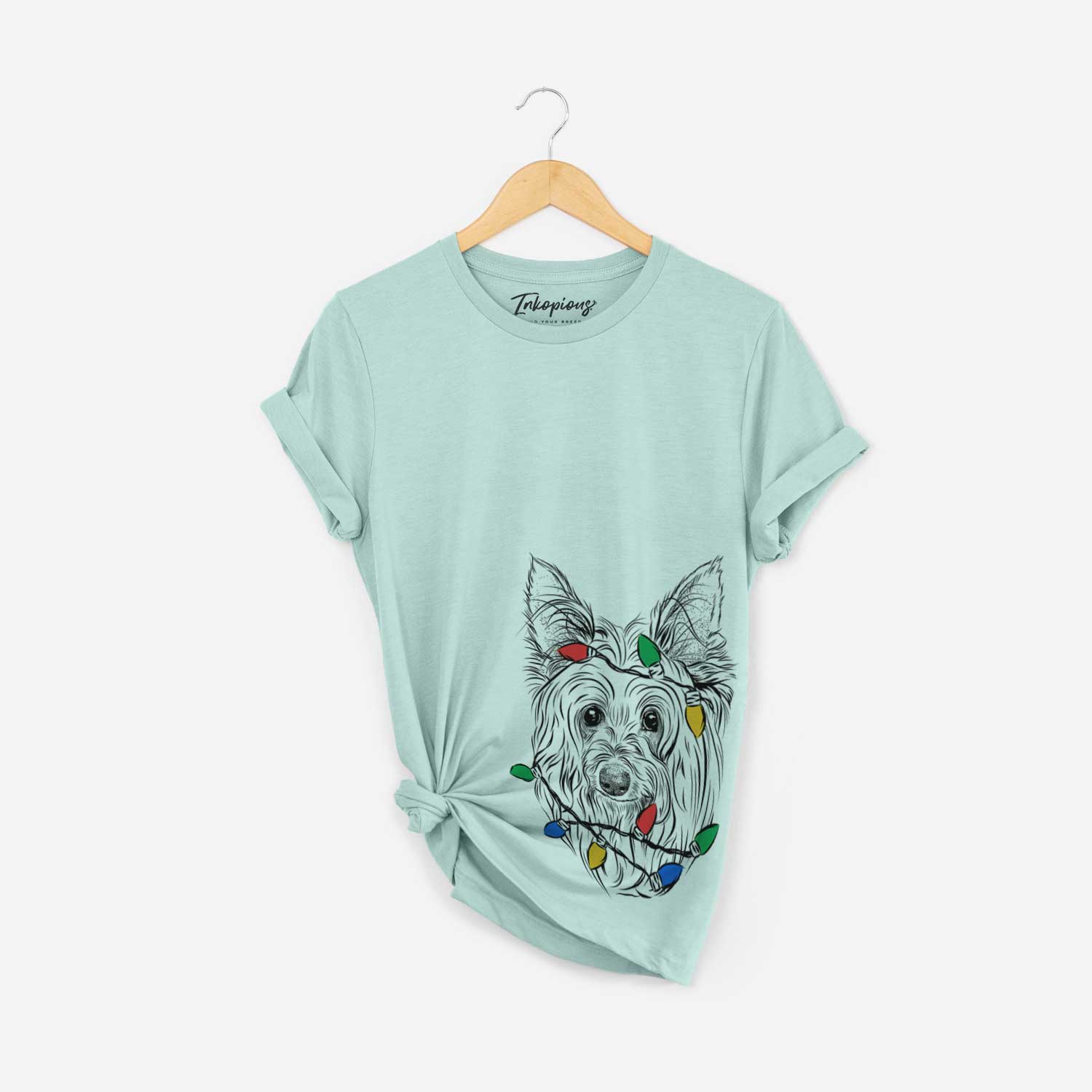 Hand-drawn sketch of Daisy May the Silky Terrier wrapped in Christmas lights on a Heather Sage Unisex crewneck