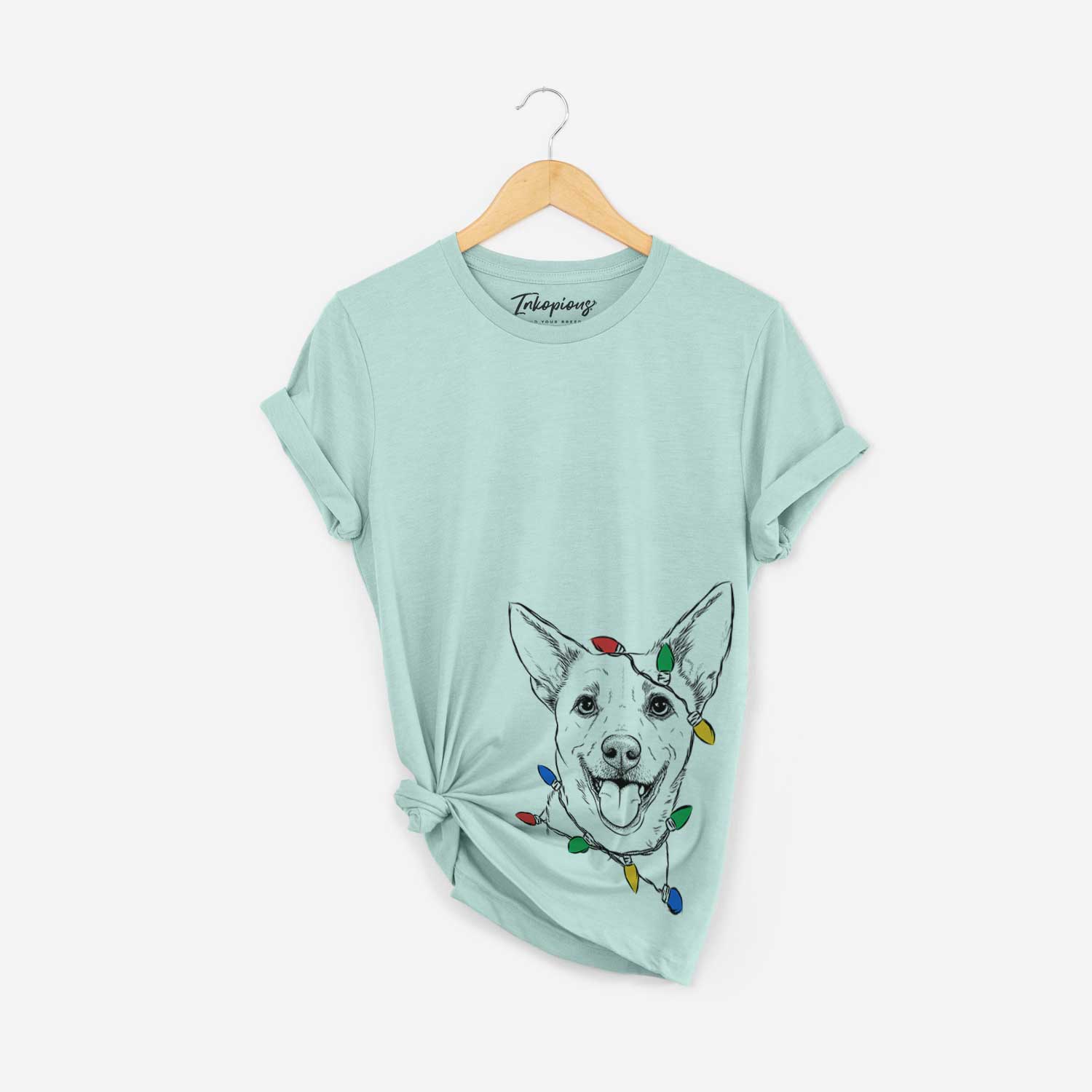 Hand-drawn sketch of Dinghy the Mixed Breed wrapped in Christmas lights on a Heather Sage Unisex crewneck