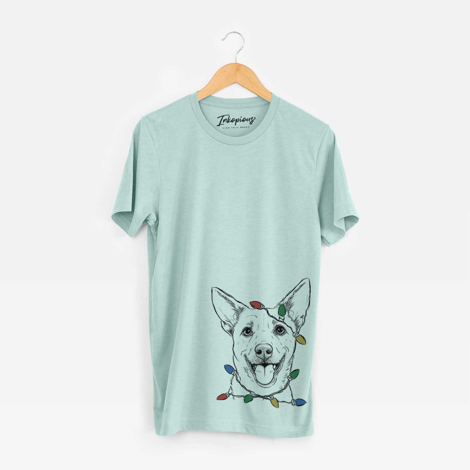 Hand-drawn sketch of Dinghy the Mixed Breed wrapped in Christmas lights on a Heather Sage Unisex crewneck
