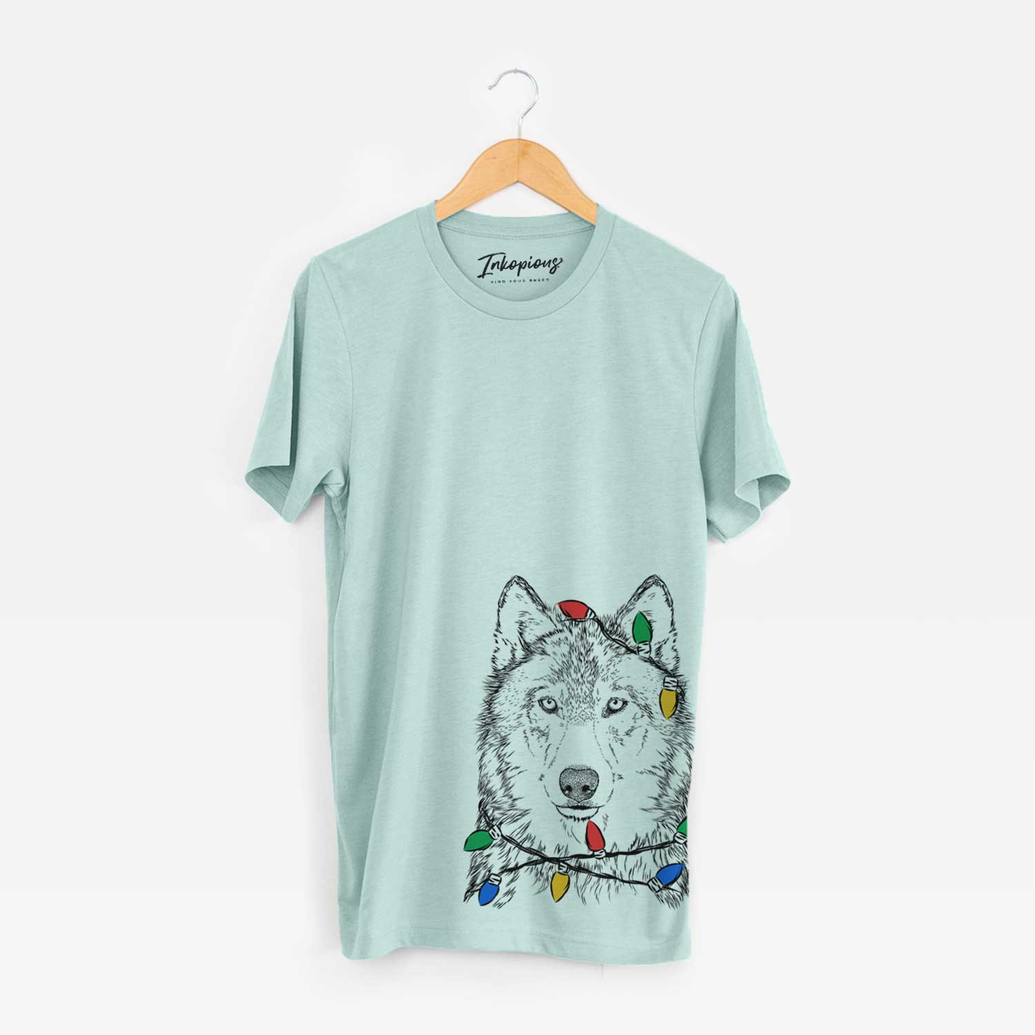 Hand-drawn sketch of Django the Grey Wolf wrapped in Christmas lights on a Heather Sage Unisex crewneck