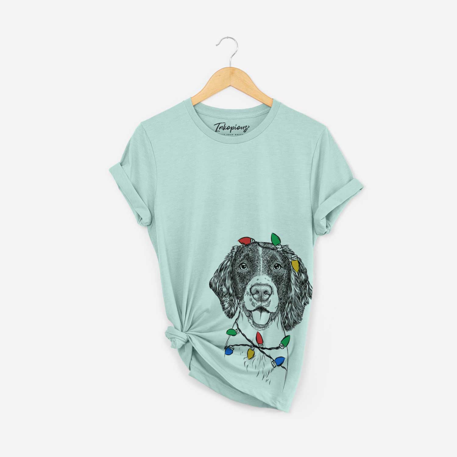 Hand-drawn sketch of Ever the English Springer Spaniel wrapped in Christmas lights on a Heather Sage Unisex crewneck