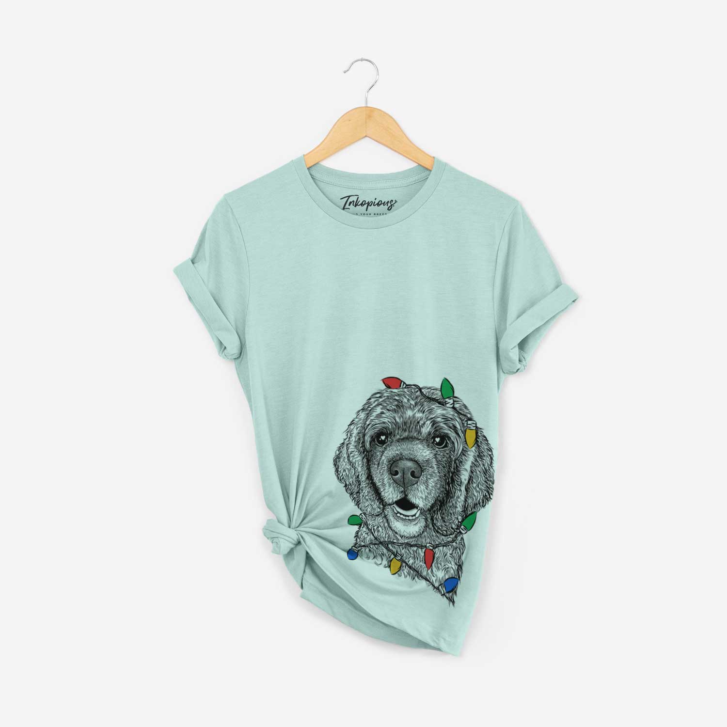 Hand-drawn sketch of Fannie Mae the Cocker Spaniel wrapped in Christmas lights on a Heather Sage Unisex crewneck