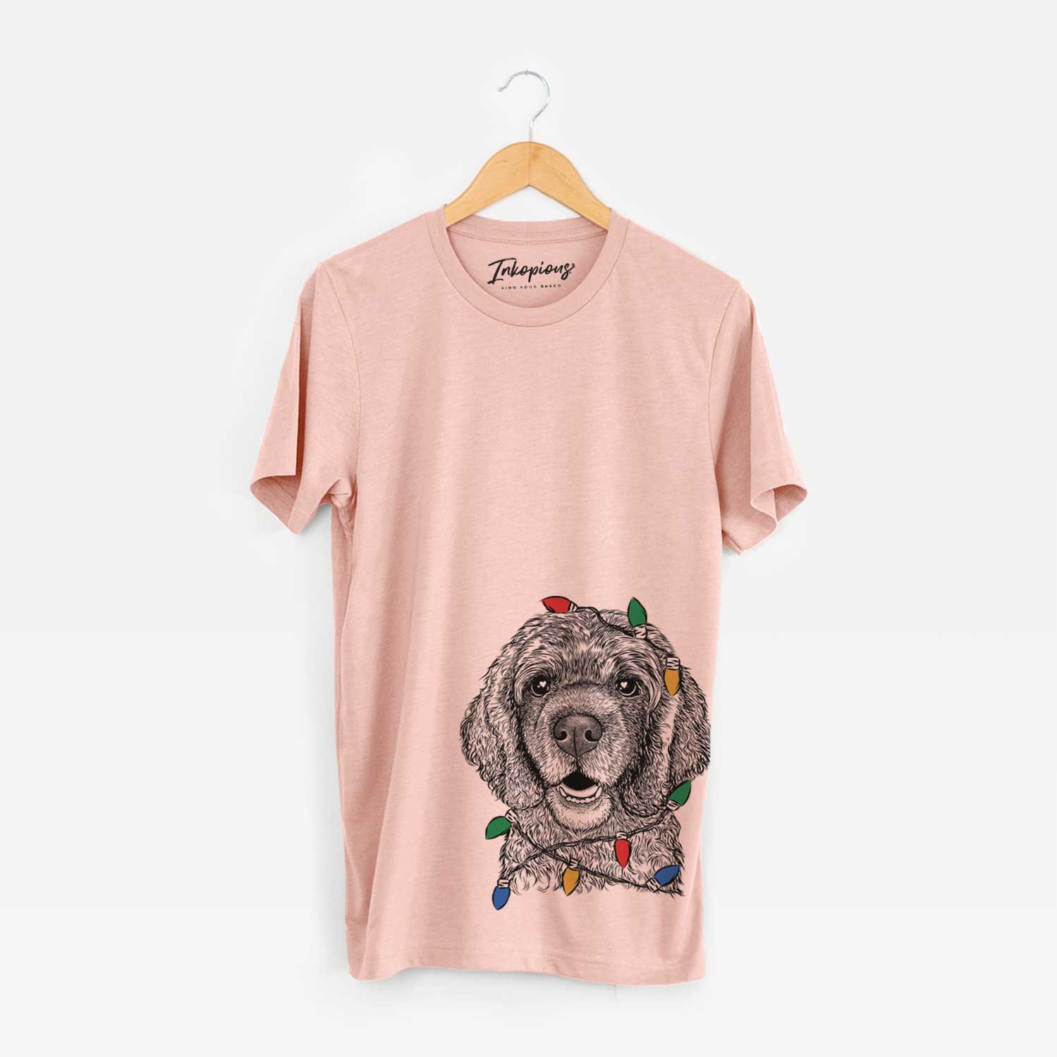 Hand-drawn sketch of Fannie Mae the Cocker Spaniel wrapped in Christmas lights on a Peach Unisex crewneck