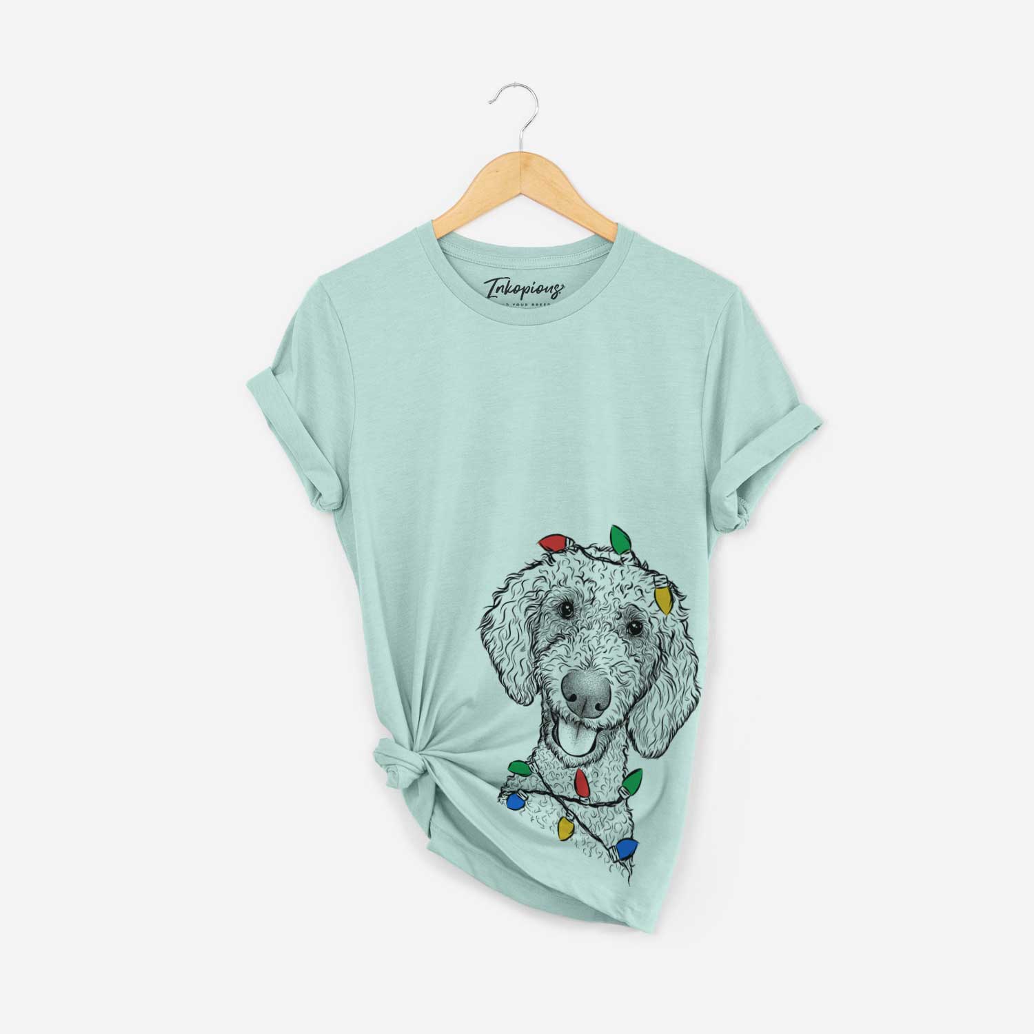 Hand-drawn sketch of Fenway the Goldendoodle wrapped in Christmas lights on a Heather Sage Unisex crewneck