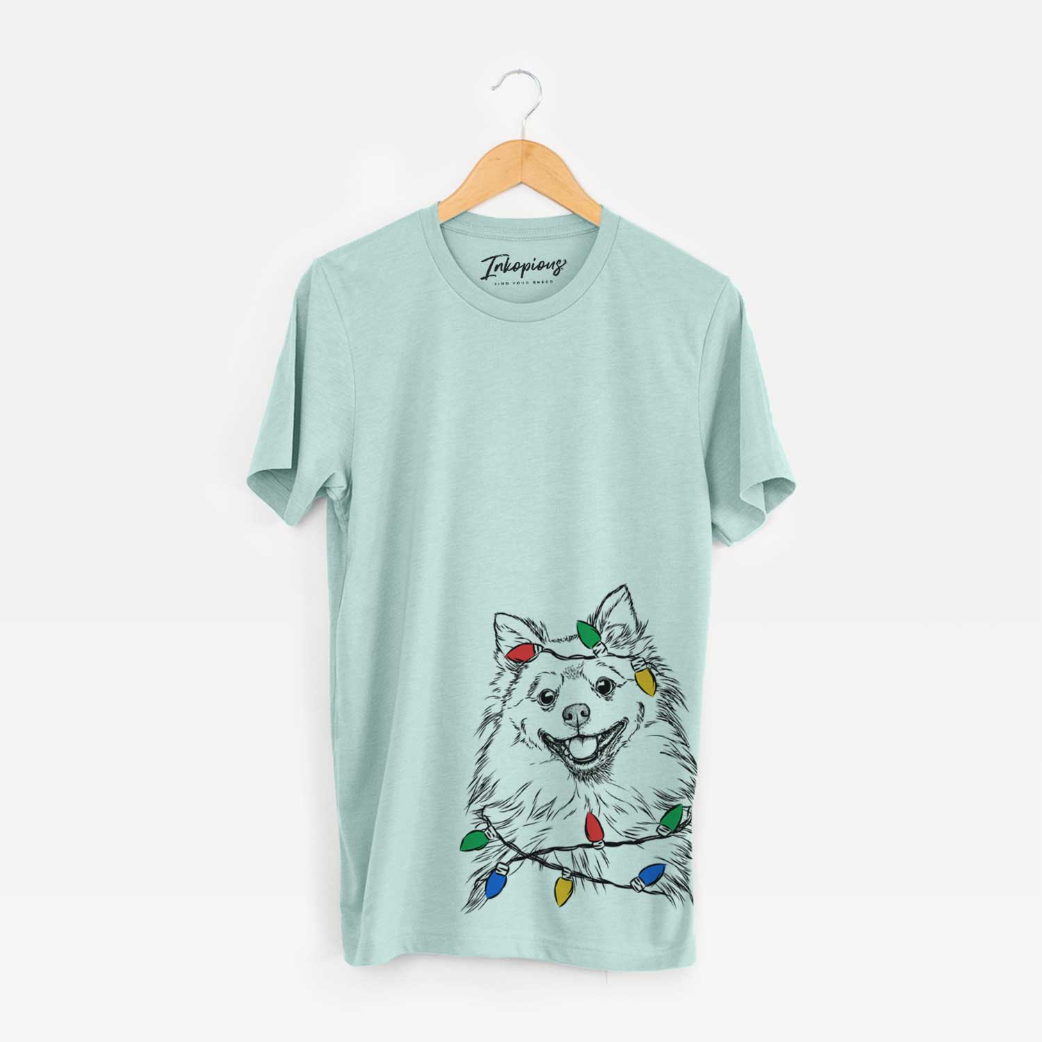 Hand-drawn sketch of Fibi the Spitz wrapped in Christmas lights on a Heather Sage Unisex crewneck