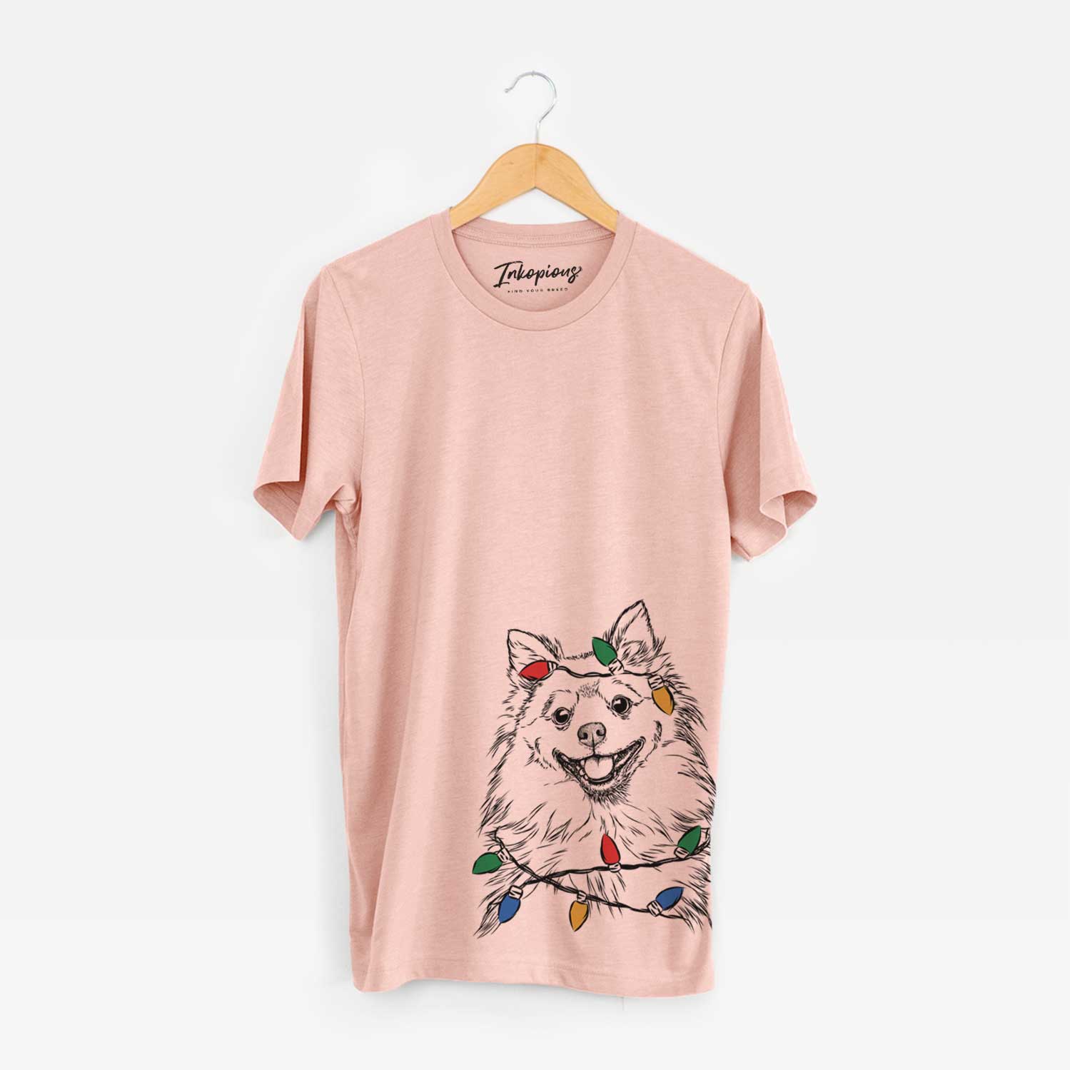 Hand-drawn sketch of Fibi the Spitz wrapped in Christmas lights on a Peach Unisex crewneck