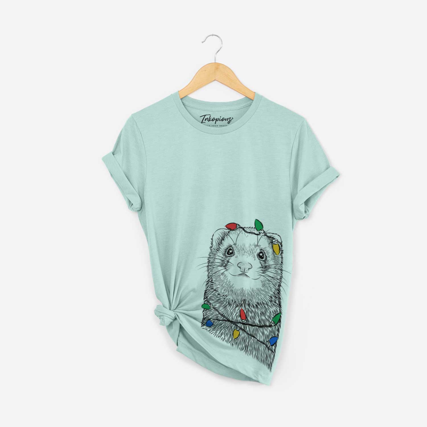 Hand-drawn sketch of Fig the Ferret wrapped in Christmas lights on a Heather Sage Unisex crewneck