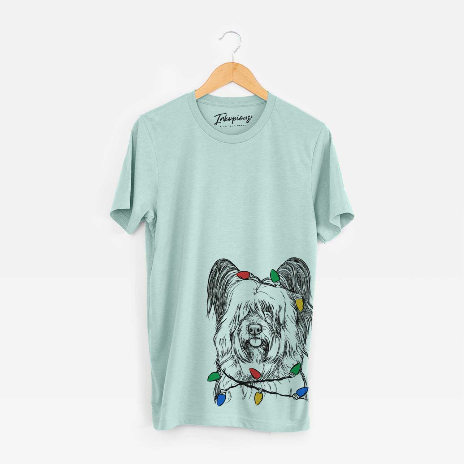 Hand-drawn sketch of Gideon the Skye Terrier wrapped in Christmas lights on a Heather Sage Unisex crewneck