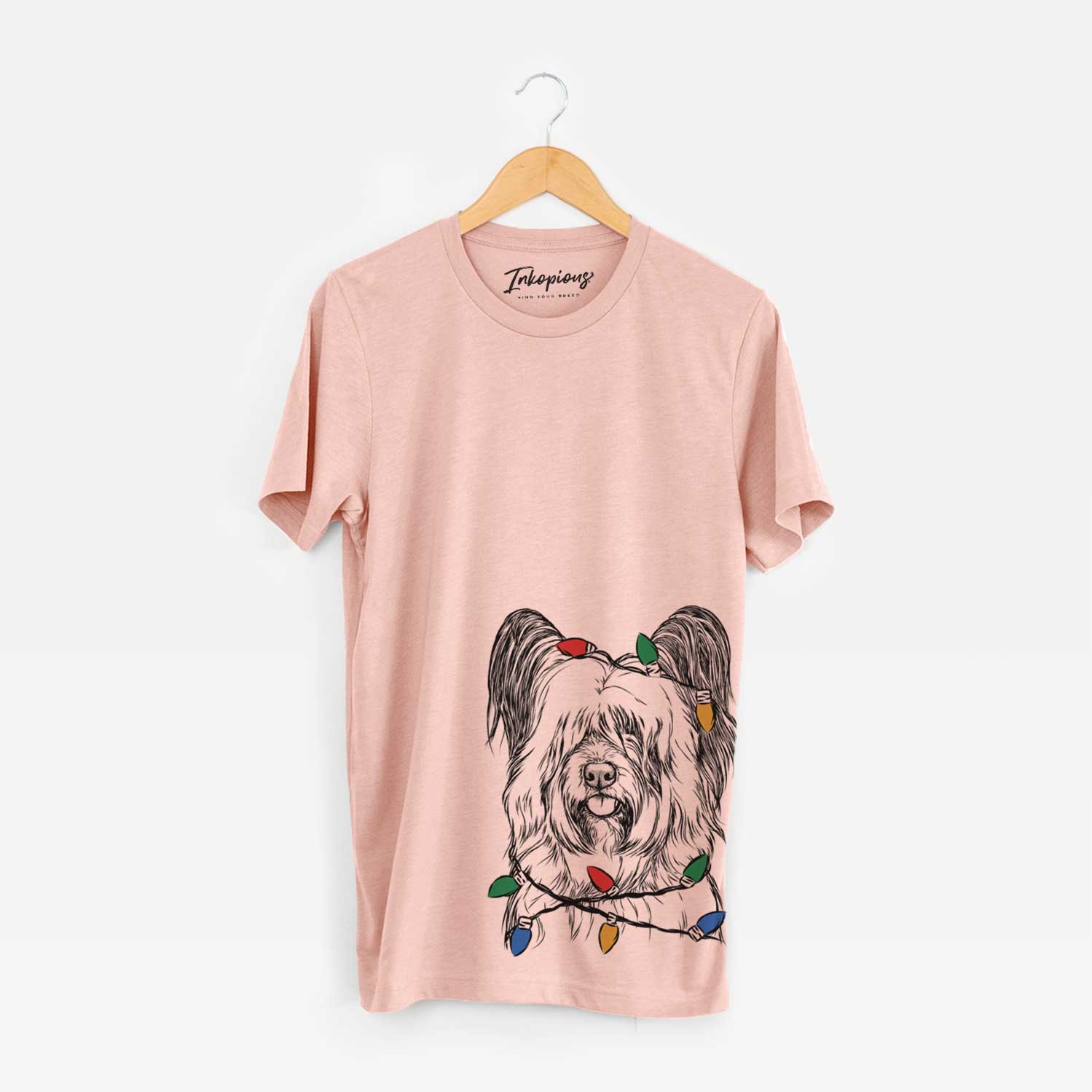 Hand-drawn sketch of Gideon the Skye Terrier wrapped in Christmas lights on a Peach Unisex crewneck