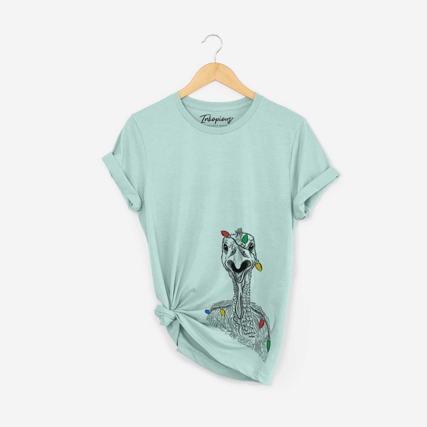 Hand-drawn sketch of Gobble the Turkey wrapped in Christmas lights on a Heather Sage Unisex crewneck
