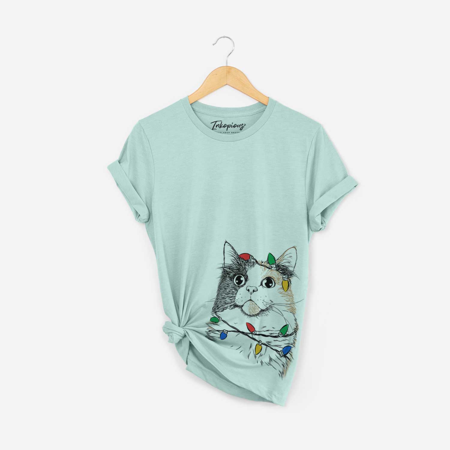 Hand-drawn sketch of Greta the Calico Cat wrapped in Christmas lights on a Heather Sage Unisex crewneck