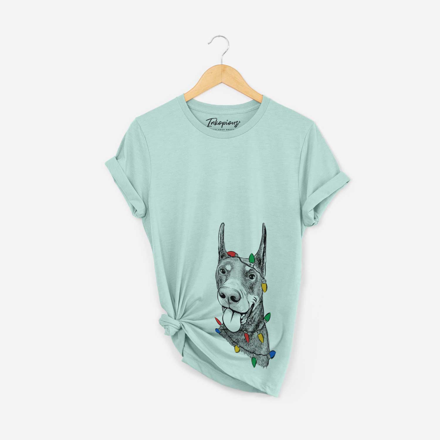 Hand-drawn sketch of Happy Sunny the Doberman Pinscher wrapped in Christmas lights on a Heather Sage Unisex crewneck