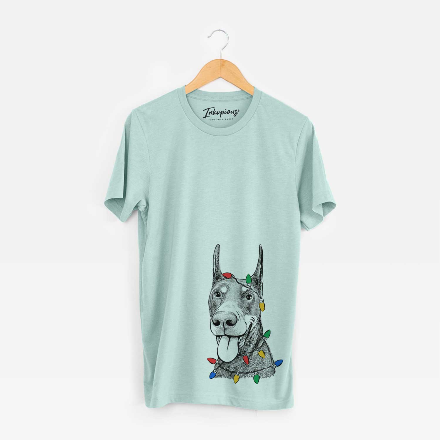 Hand-drawn sketch of Happy Sunny the Doberman Pinscher wrapped in Christmas lights on a Heather Sage Unisex crewneck