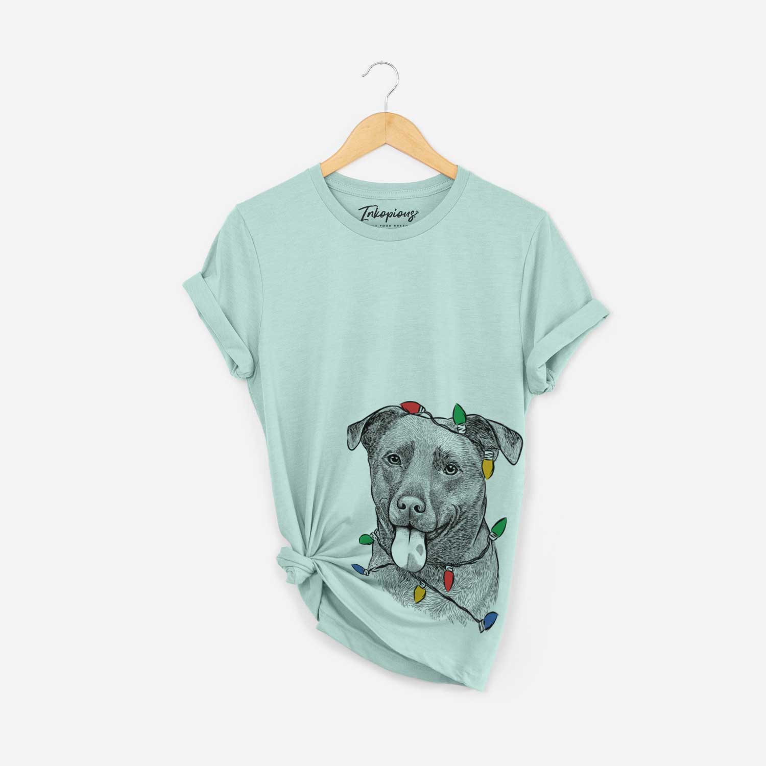 Hand-drawn sketch of Harbor the Mixed Breed wrapped in Christmas lights on a Heather Sage Unisex crewneck