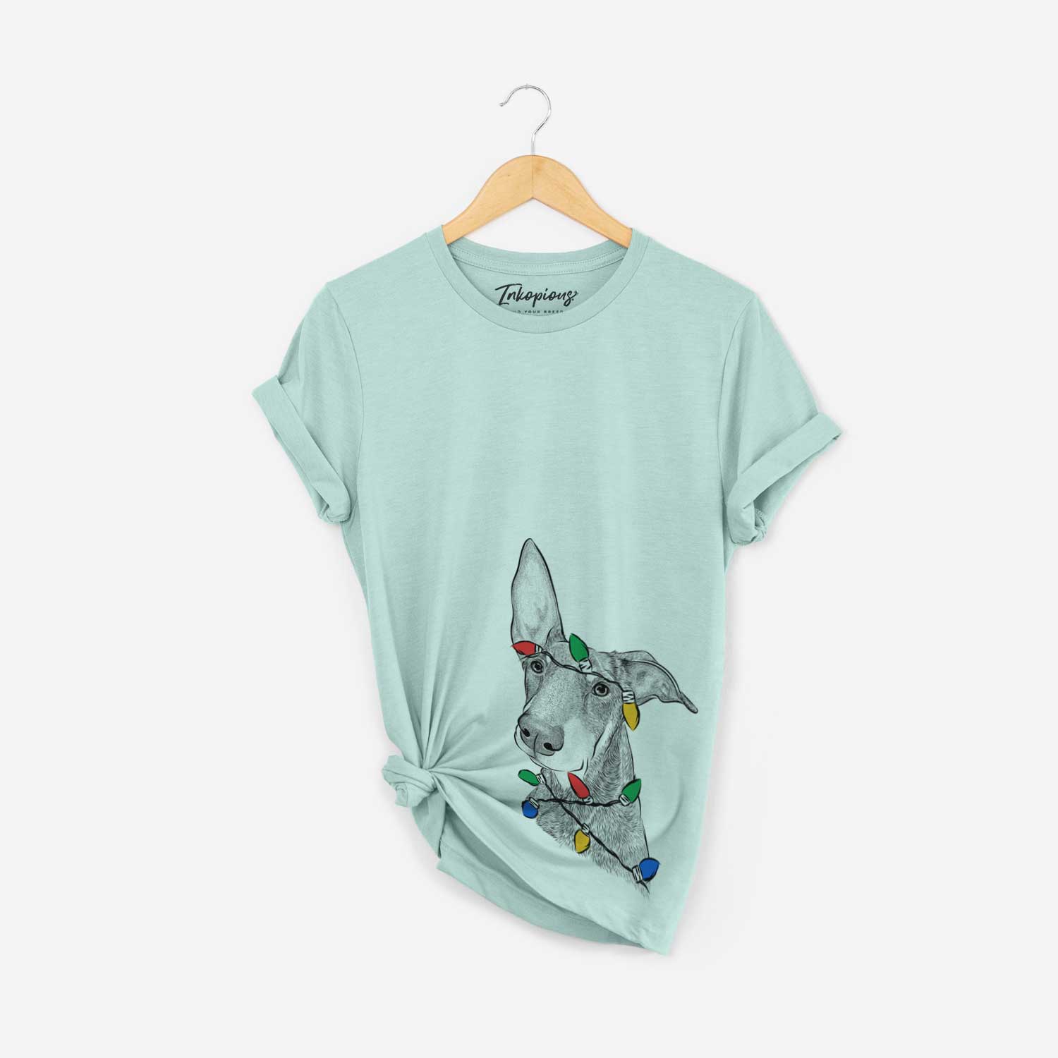 Hand-drawn sketch of Kain the Doberman Pinscher wrapped in Christmas lights on a Heather Sage Unisex crewneck