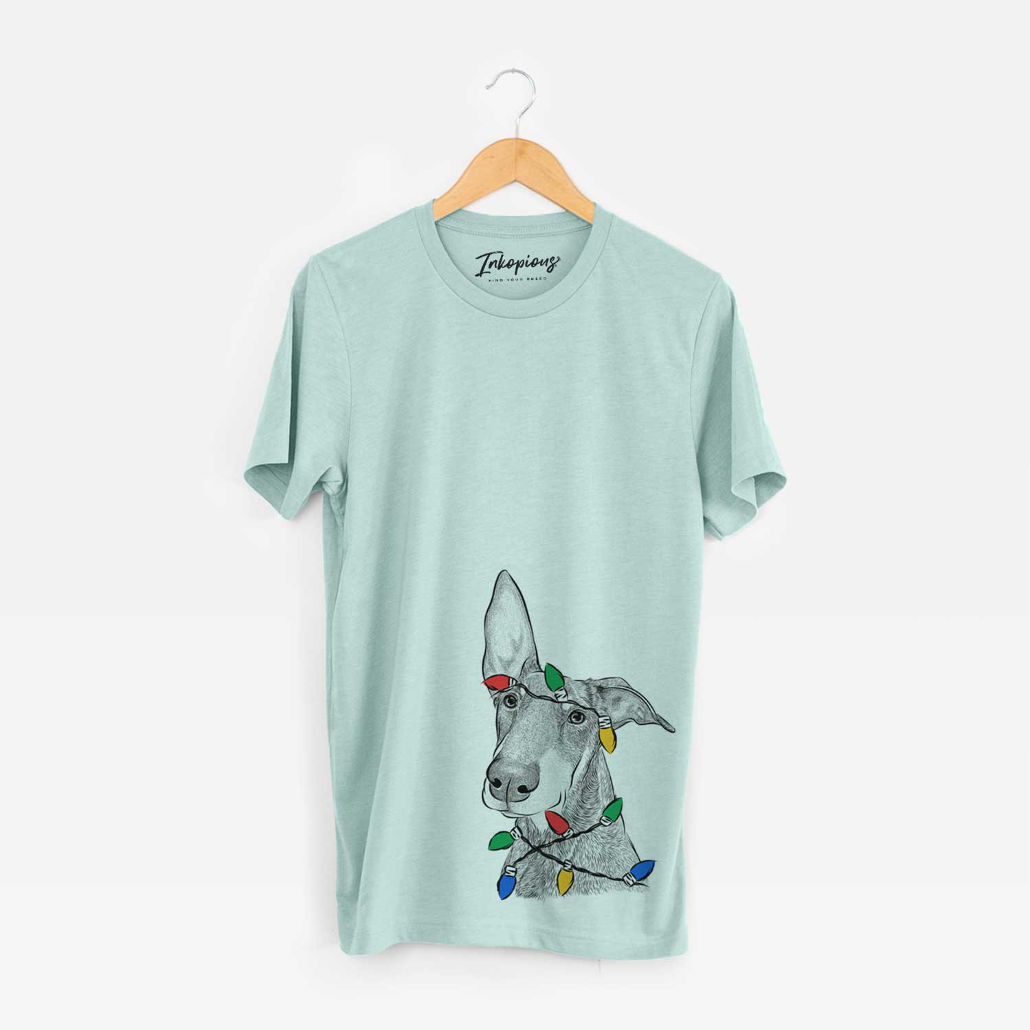 Hand-drawn sketch of Kain the Doberman Pinscher wrapped in Christmas lights on a Heather Sage Unisex crewneck