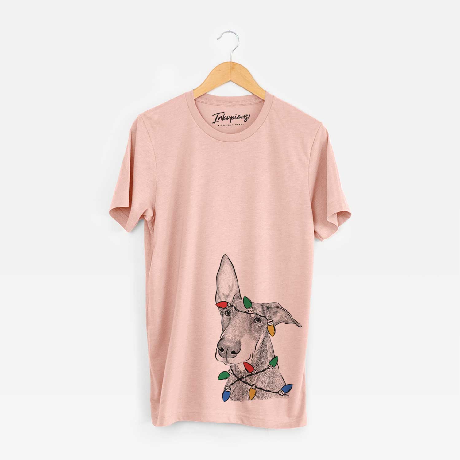 Hand-drawn sketch of Kain the Doberman Pinscher wrapped in Christmas lights on a Peach Unisex crewneck