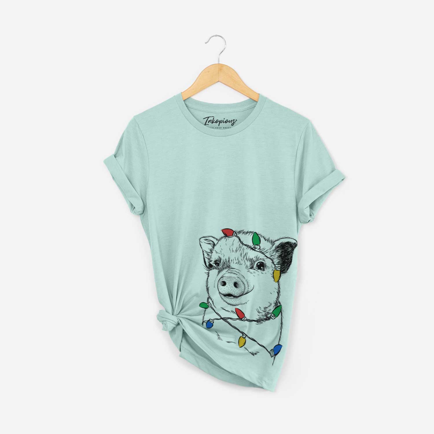 Hand-drawn sketch of Kevin the Spotted Pig wrapped in Christmas lights on a Heather Sage Unisex crewneck