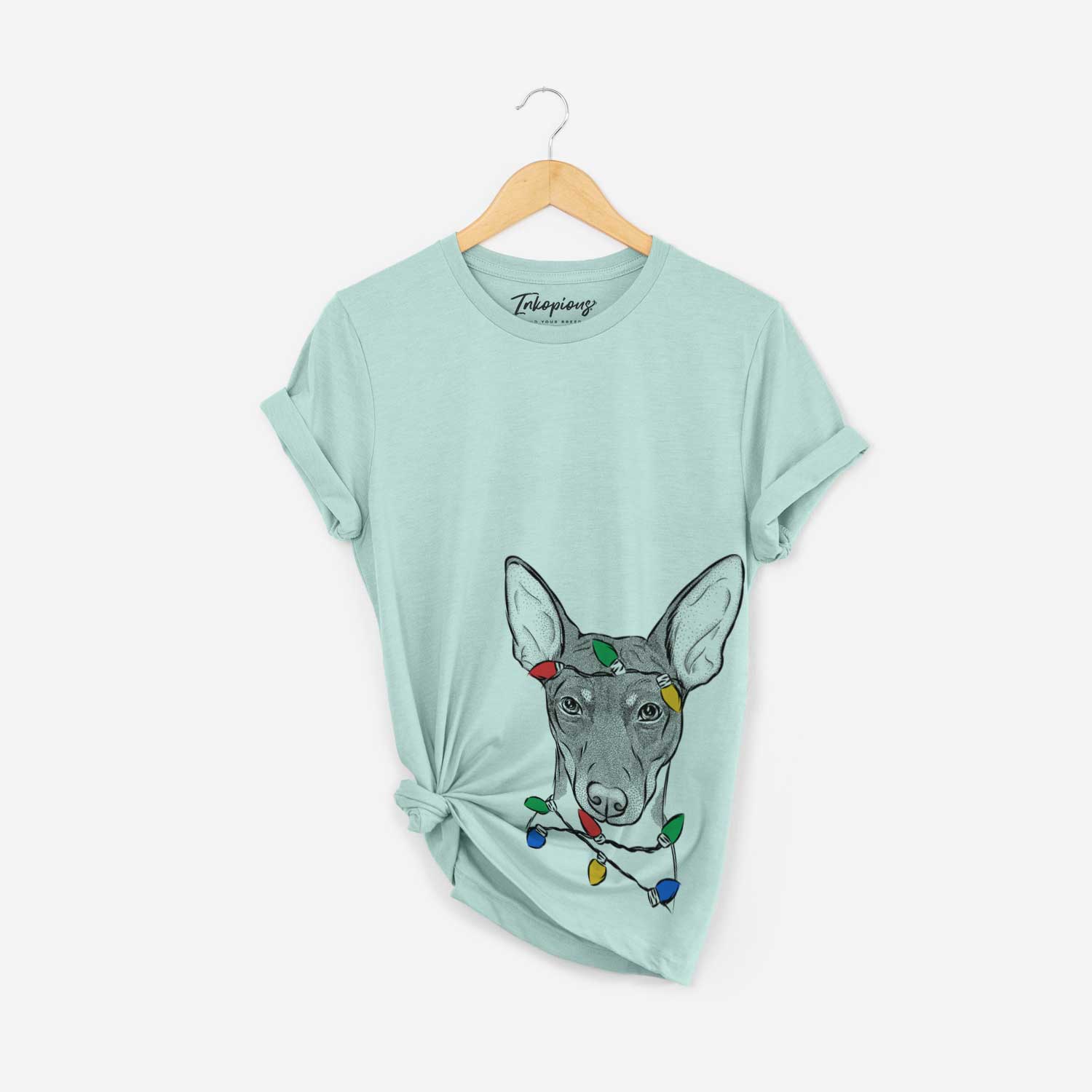 Hand-drawn sketch of Knox the Rat Terrier wrapped in Christmas lights on a Heather Sage Unisex crewneck