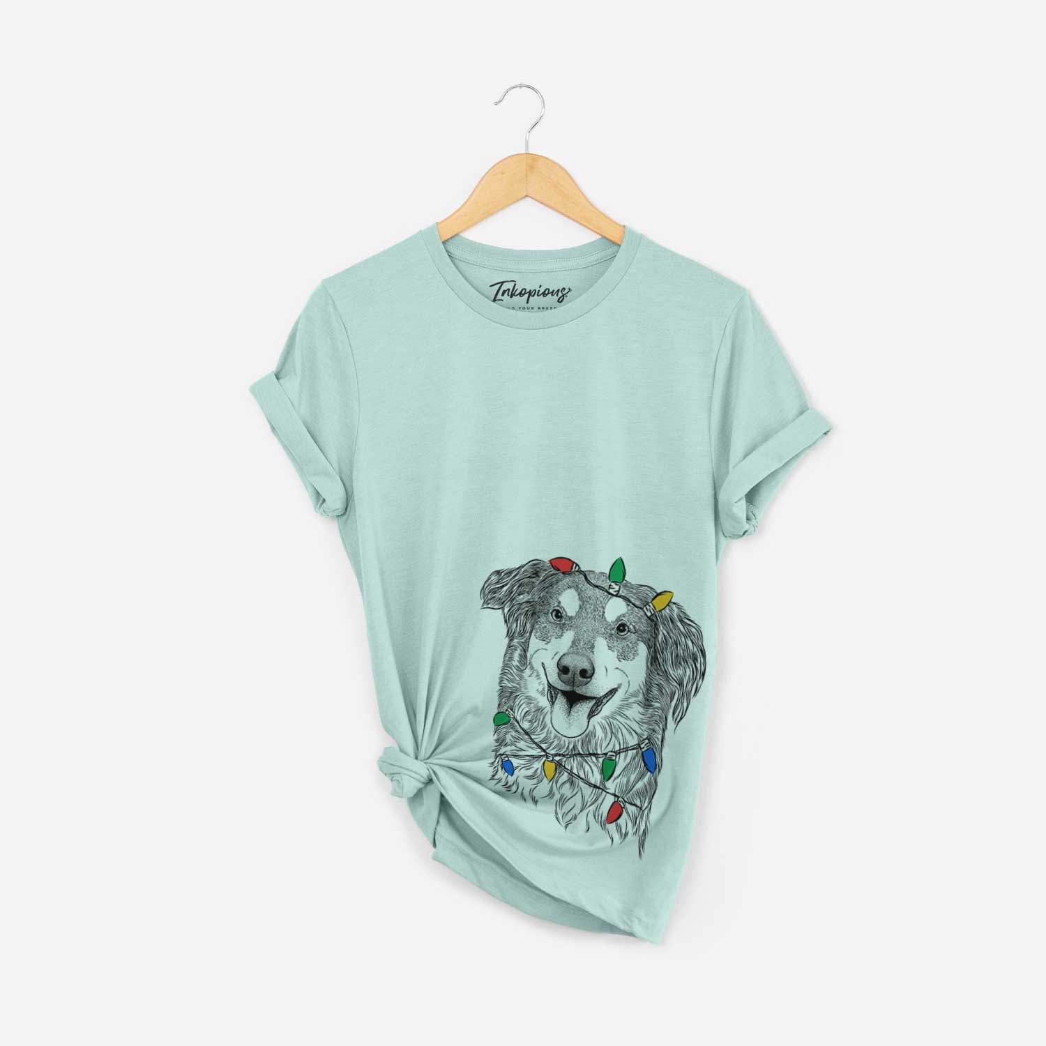 Hand-drawn sketch of Maddie the English Shepherd wrapped in Christmas lights on a Heather Sage Unisex crewneck
