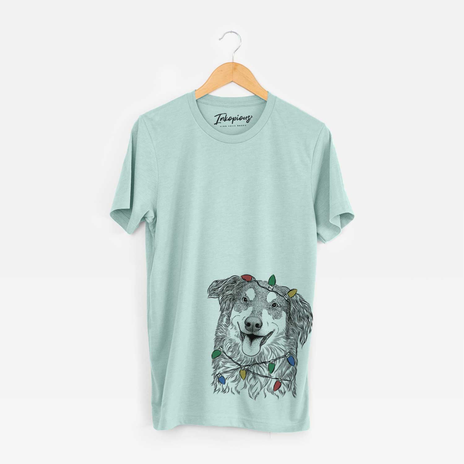 Hand-drawn sketch of Maddie the English Shepherd wrapped in Christmas lights on a Heather Sage Unisex crewneck