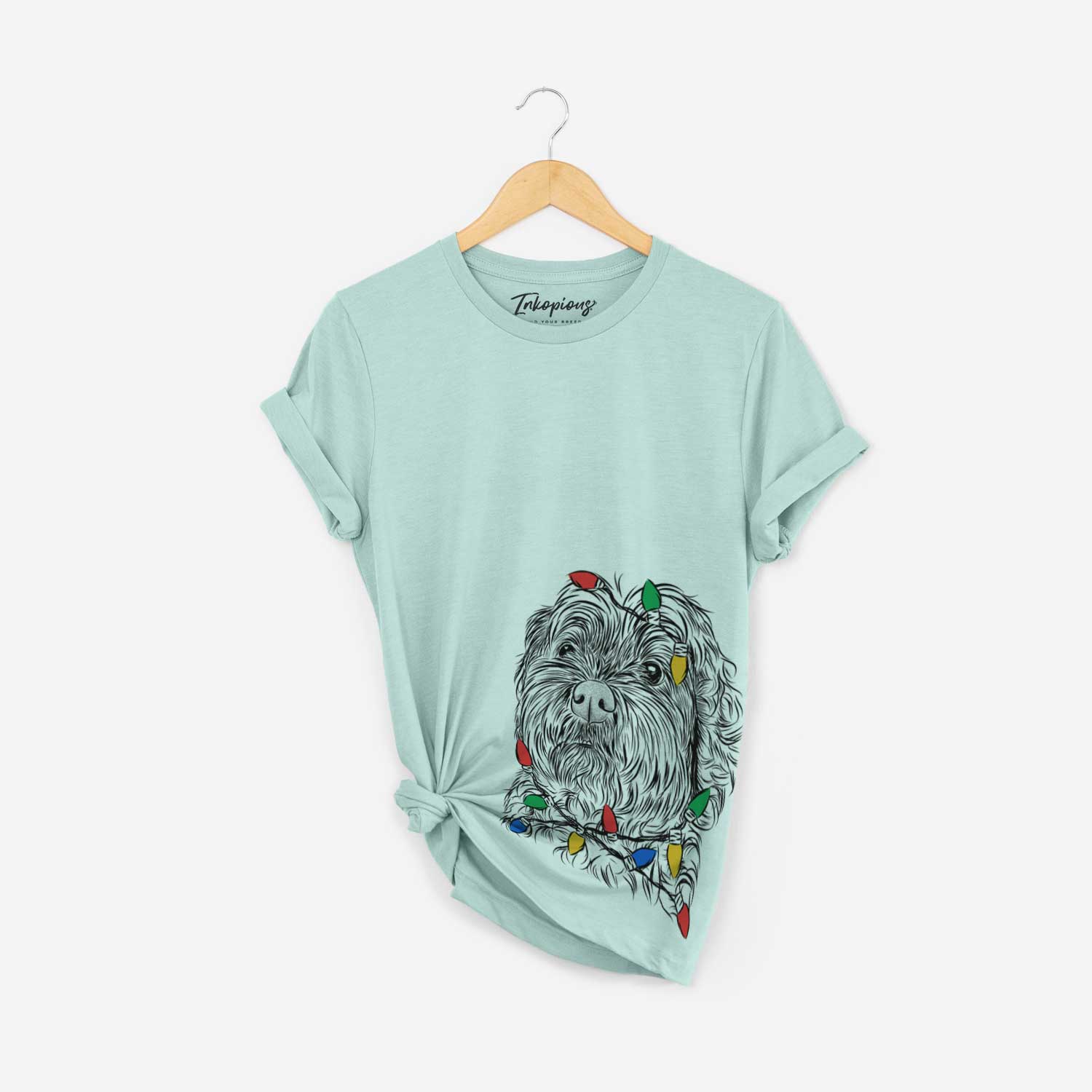 Hand-drawn sketch of Maggie Girl the Cockapoo wrapped in Christmas lights on a Heather Sage Unisex crewneck